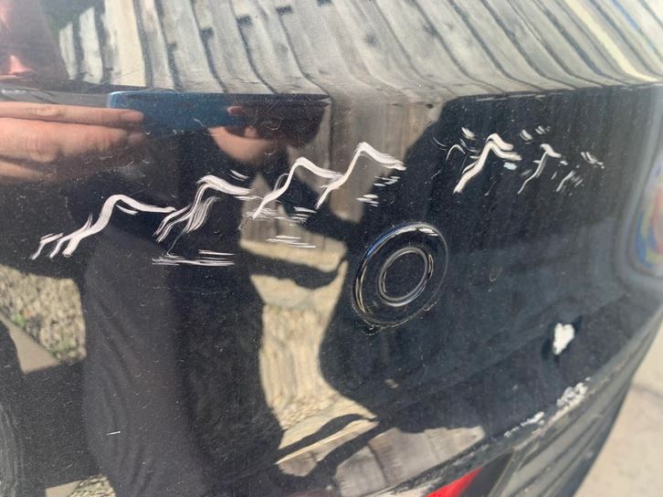 Poškriabaný čierny lak na aute so zreteľnými škrabancami, detailný záber na poškodenie karosérie.