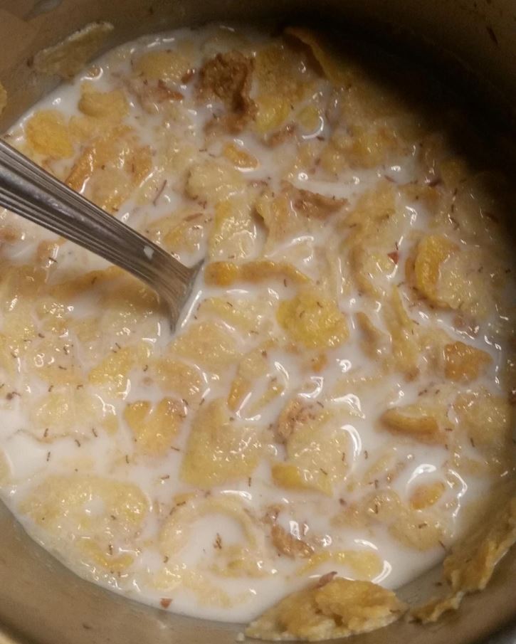 Miska cereálií v mlieku s lyžicou, pripravená na raňajkové potešenie.