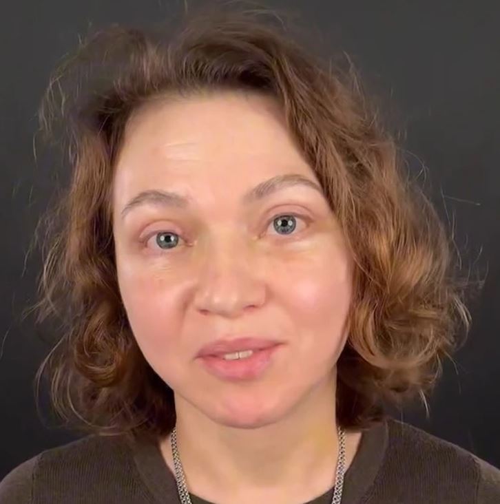 Osoba s vlnitými vlasmi na tmavom pozadí, vyjadrujúca pokoj a sústredenie.