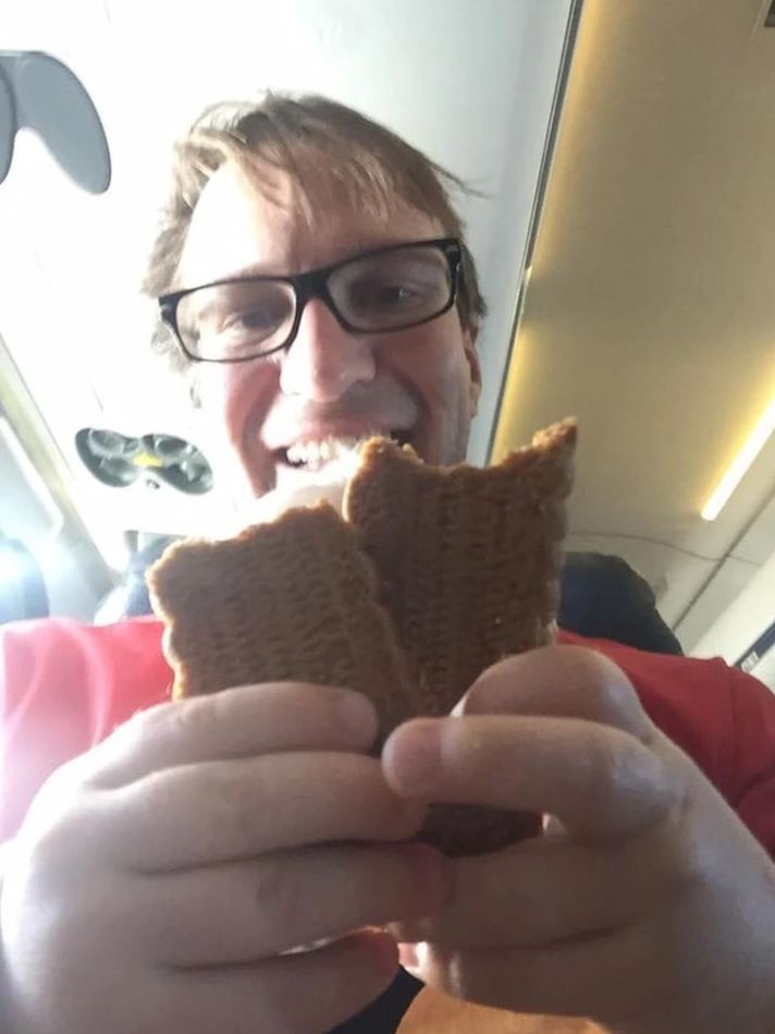 Osoba usmievajúc sa drží keksíky vo vnútri dopravného prostriedku, pravdepodobne v lietadle.