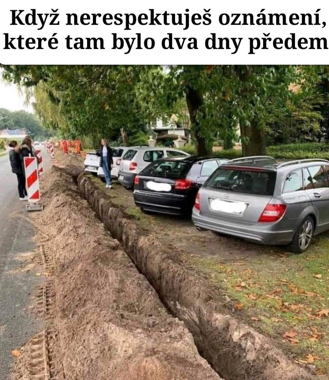 Autá zaparkované vedľa výkopu pri ceste, ignorované výstrahy o stavebných prácach.