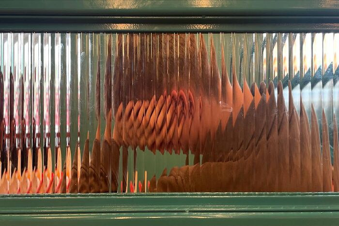 Pohľad cez sklenenú textúru s optickým efektom tvoriacim abstraktný obraz nejasných tvarov a farieb.