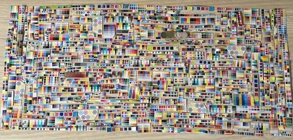 Farebná mozaika z recyklovaného materiálu na drevenom povrchu, plná rôznych vzorov a odtieňov.