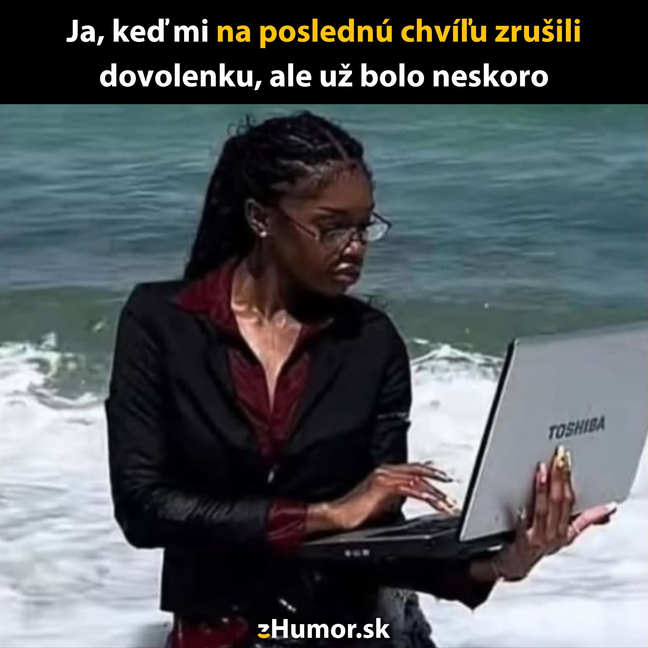 Žena v obleku s laptopom stojí po kolená vo vode na pláži.
