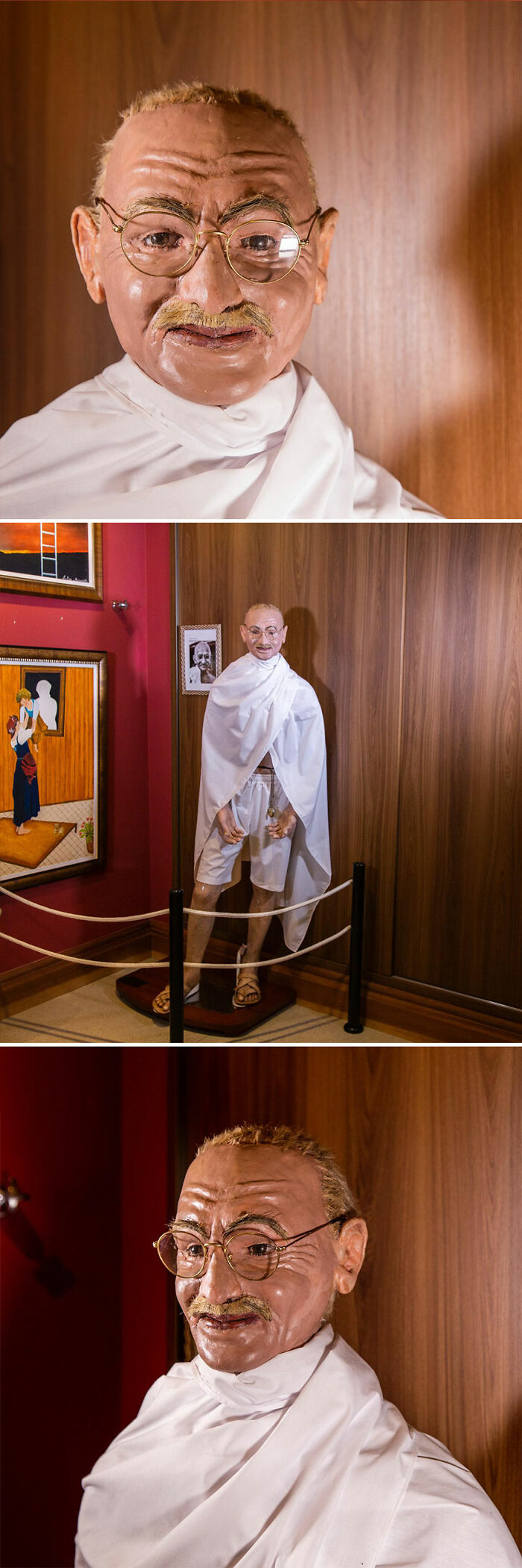 Socha historickej osobnosti v bielom rúchu a s okuliarmi, vystavená v múzeu s dreveným pozadím.