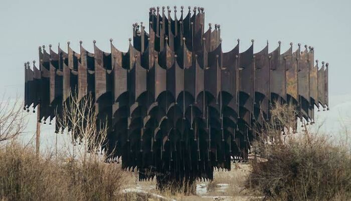 Nevšedná kovová štruktúra uprostred prírody, pripomínajúca futuristickú umeleckú inštaláciu.