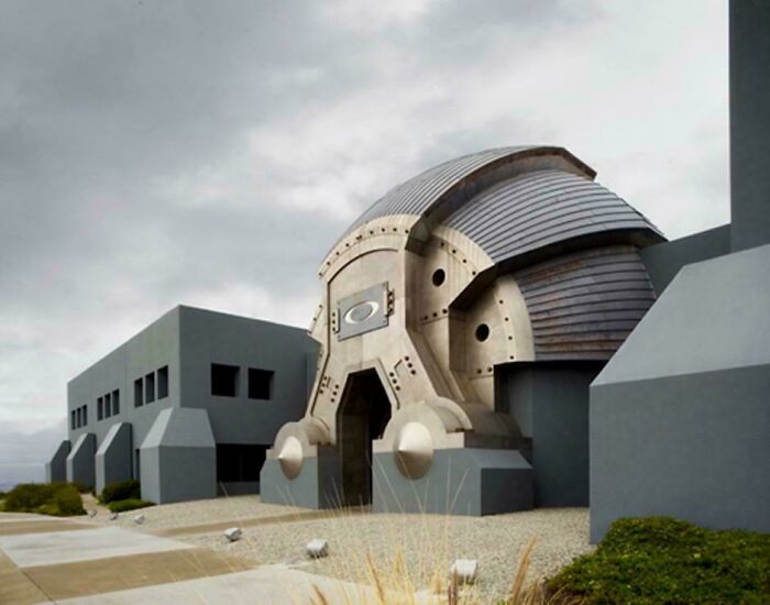 Futuristická budova s unikátnym dizajnom a oblými metalickými prvkami pod zamračenou oblohou.