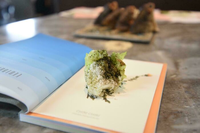 Pokrm servírovaný na knihách, kreatívne podávanie jedla, kombinácia umenia a gastronómie.