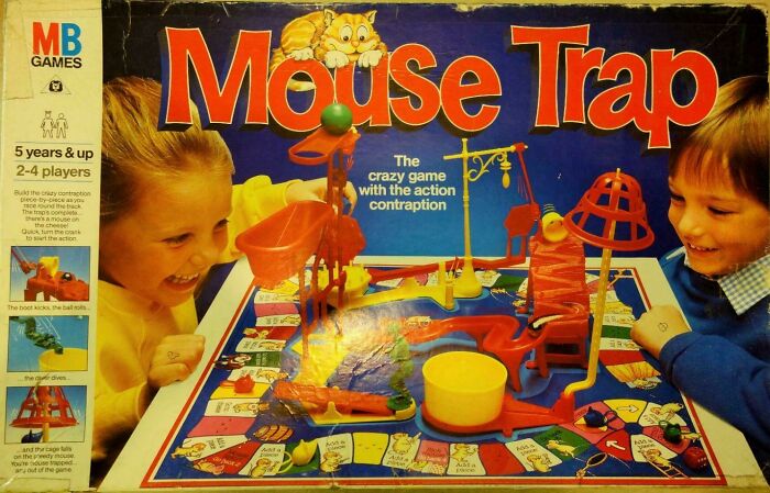 Dve deti hrajú stolnú hru Mouse Trap s farebnými prvkami na zábavnom hernom pláne od MB Games.