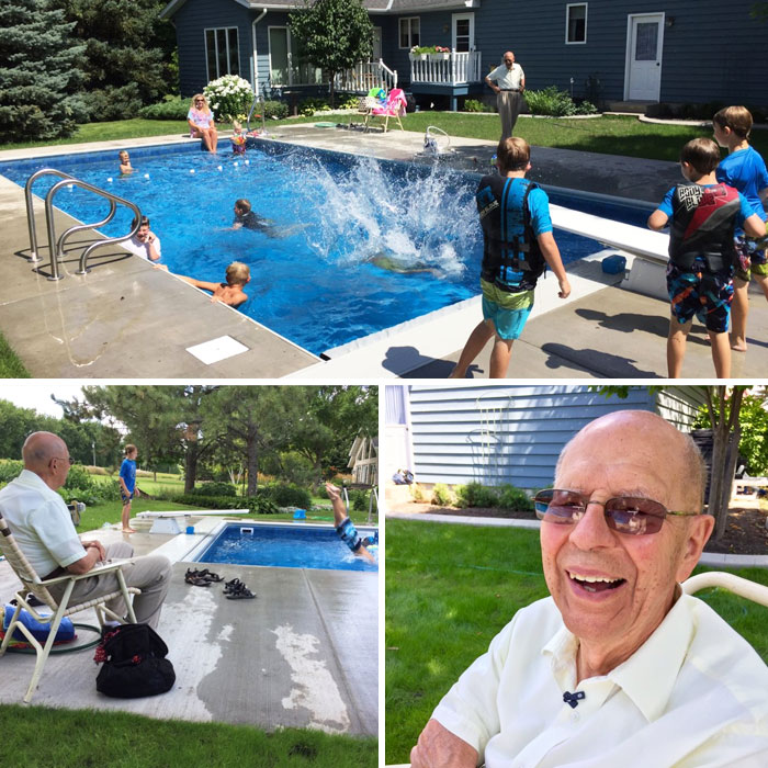 Starší muž sedí pri bazéne, sleduje deti špliechajúce vo vode v záhrade. Radostná letná atmosféra.