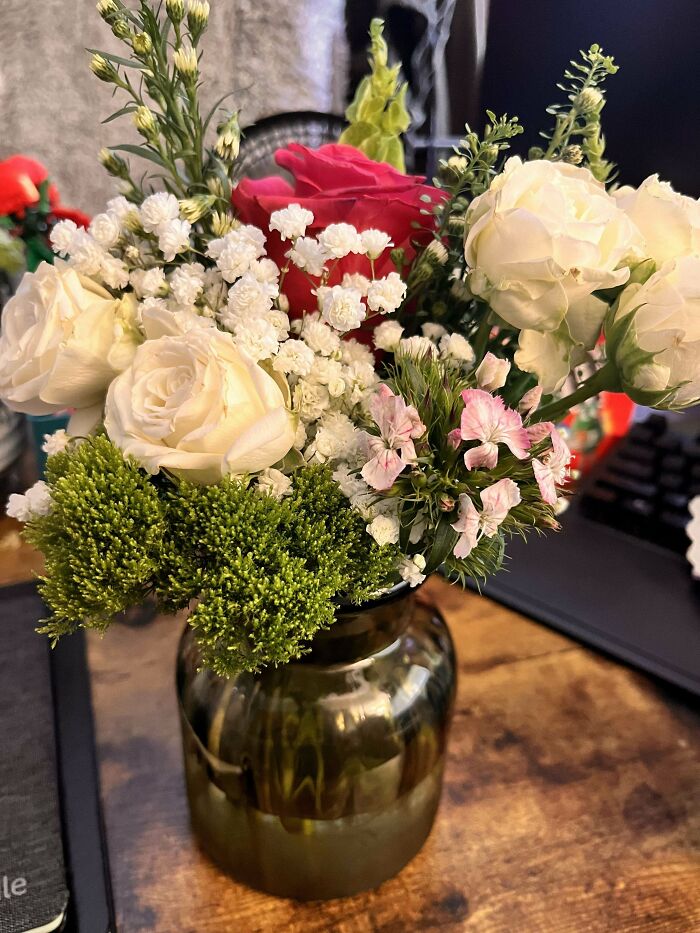 Kytica s ružami, bielymi a ružovými kvetmi vo váze na drevenom stole.