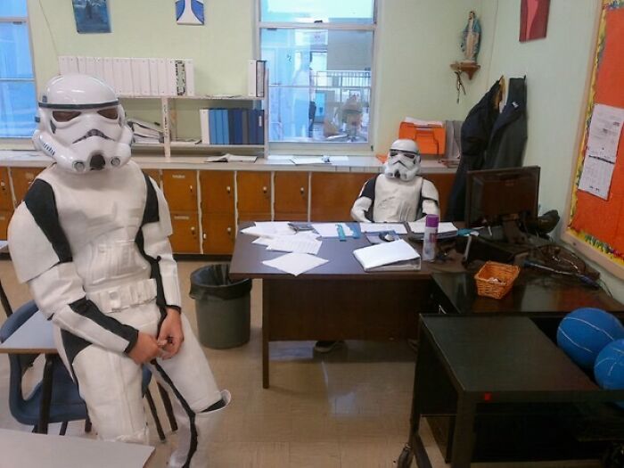 Dvaja stormtrooperi v kancelárii, jeden sedí za stolom, druhý na stoličke; neformálna pracovná atmosféra.