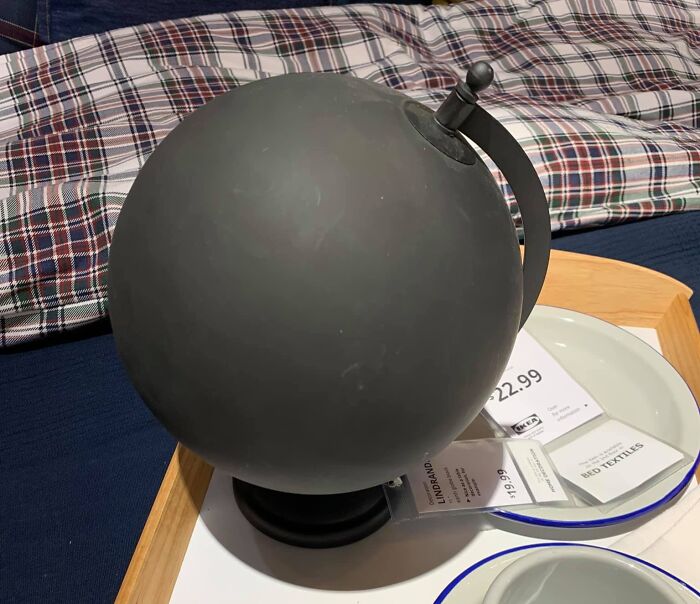 Čierny dekoratívny glóbus na stole s cenovkou v obchode nábytku.