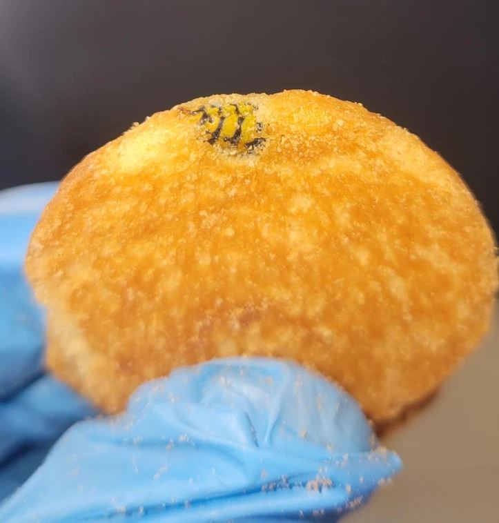 Chrumkavá vyprážaná pochúťka držiaca v rukavici, s viditeľným detailom textúry povrchu.