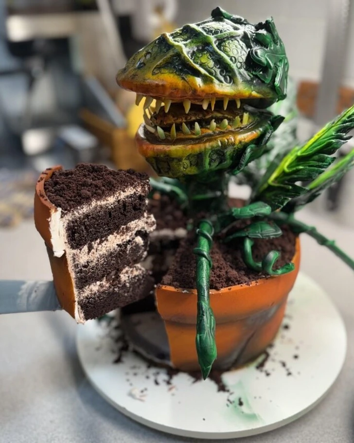 Torta v tvare mäsožravej rastliny s otvorenou čeľusťou a nakrojeným kúskom, kreatívne cukrárske dielo.