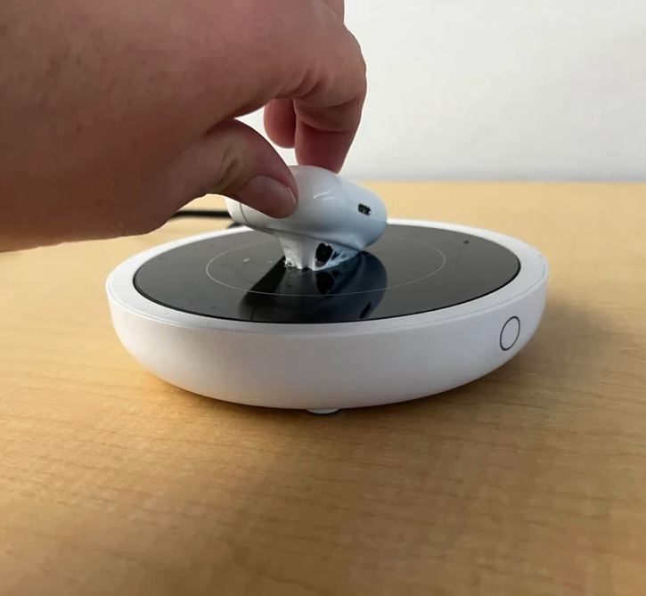 Ruka zdvíhajúca bielu myš zo špinavého nabíjacieho podstavca na drevenom stole.