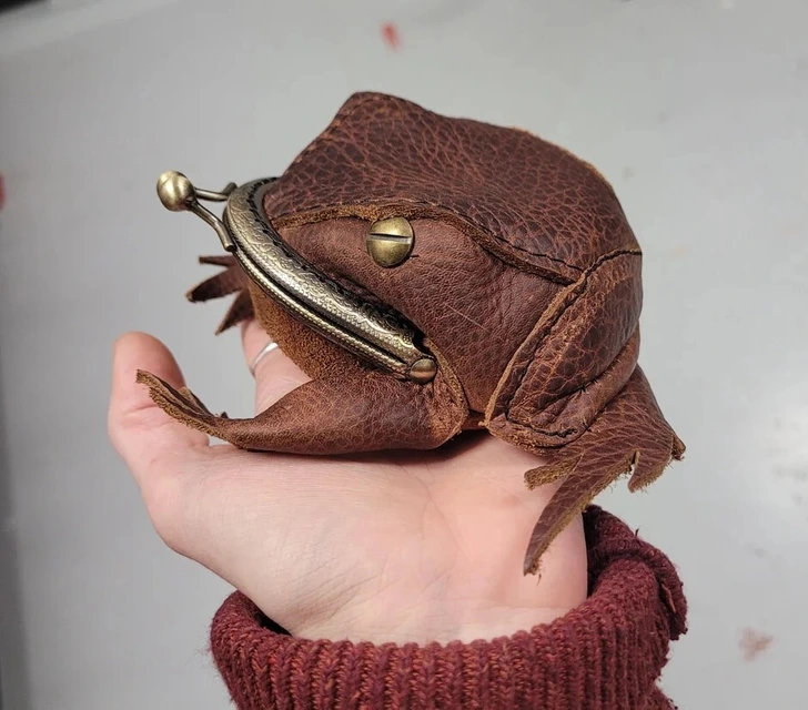 Hnedá kožená peňaženka v tvare žaby na dlani, s retro zapínaním na cvok.