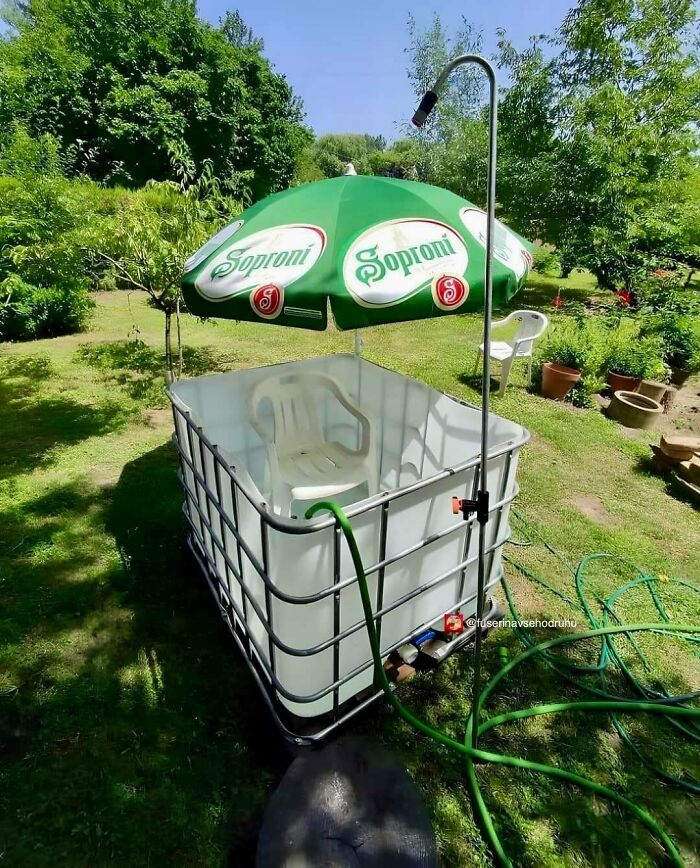 Domáci bazén z plastovej nádrže s bielym kreslom a zeleným slnečníkom v záhrade. Kreatívne letné osvieženie.