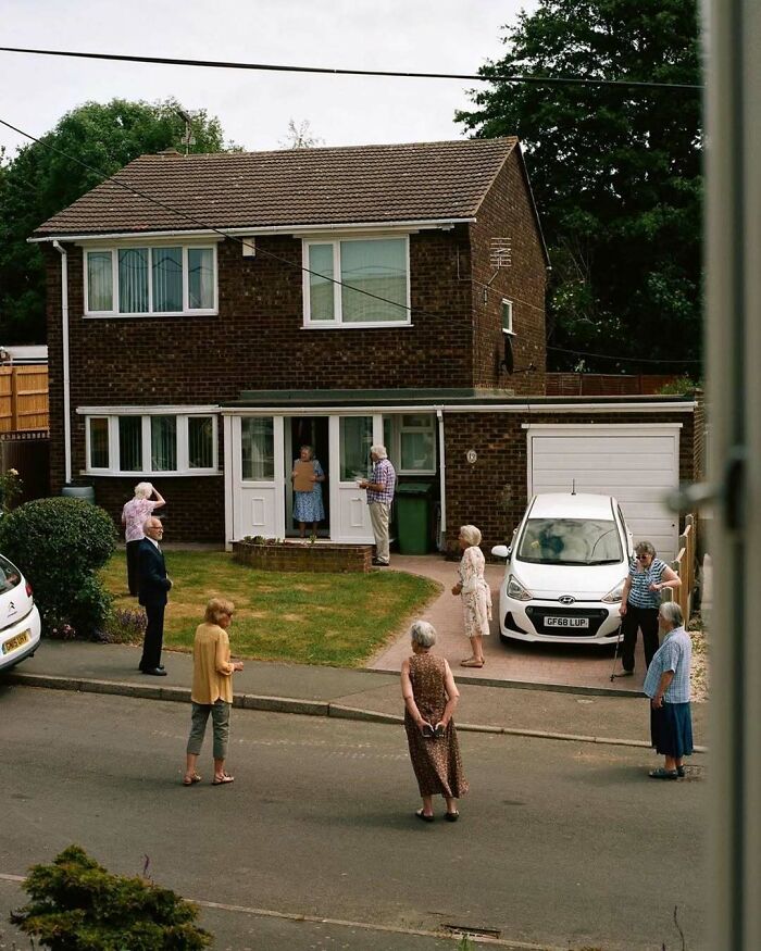 Skupina ľudí stojacich pred domom na bezpečnú vzdialenosť, dodržiavajúc opatrenia.