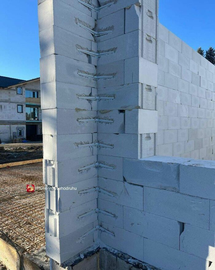 Stavba domu s viditeľným rohom murovaným z pórobetónových tvárnic na slnečný deň.