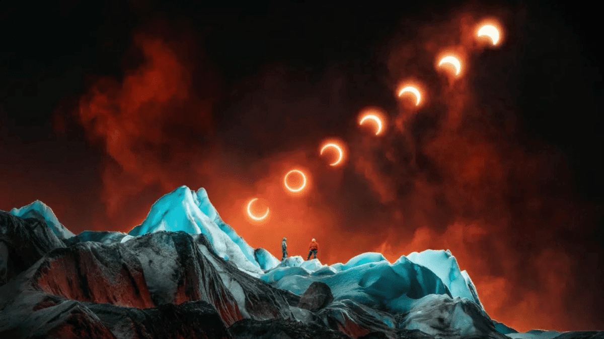 Dve osoby na ľadovej hore sledujú postupné zatmenie slnka na dramatickej oranžovej oblohe.