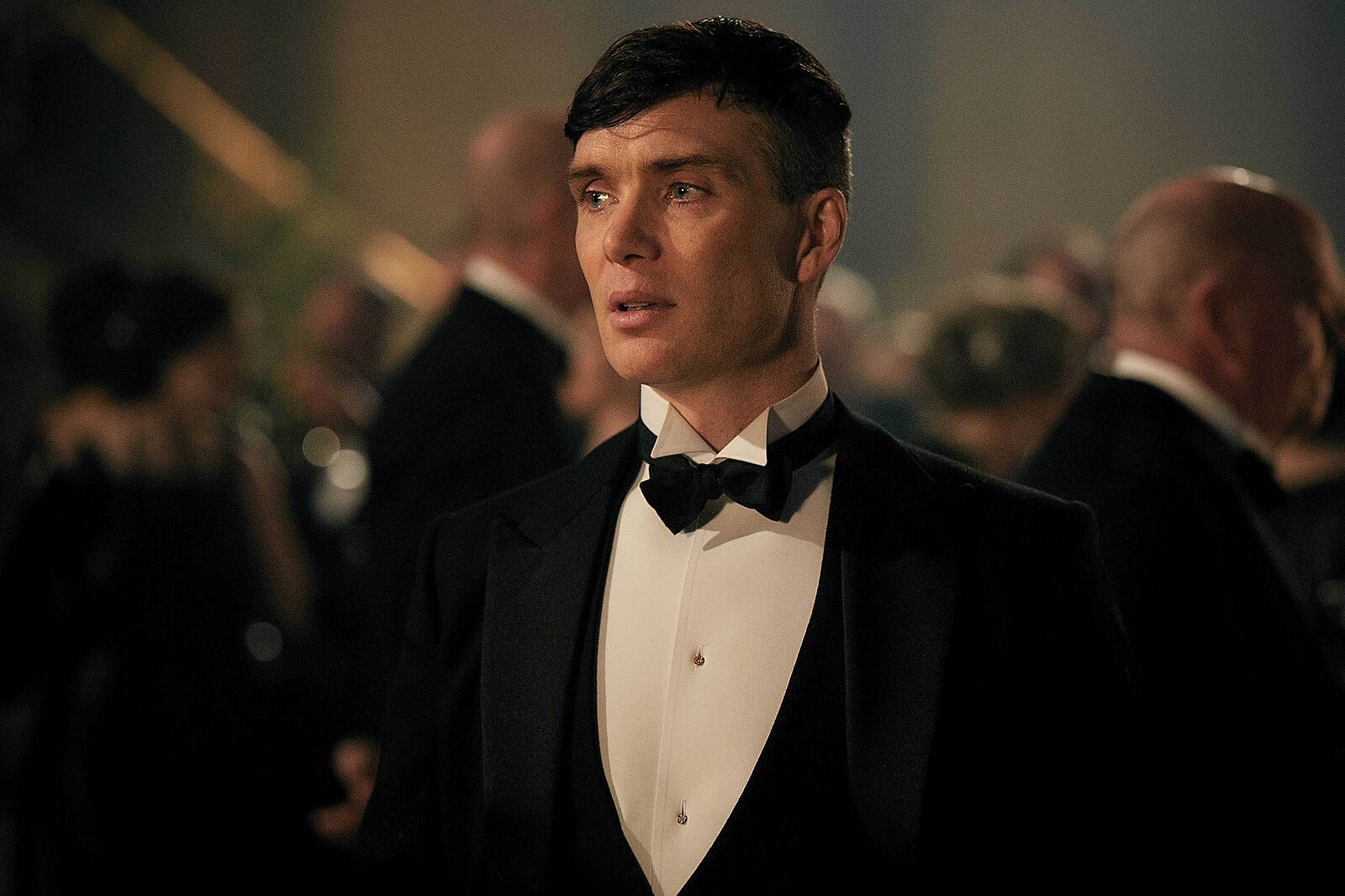 Neformálne oblečený muž v smokingu na elegantnom večierku s tlmeným osvetlením.