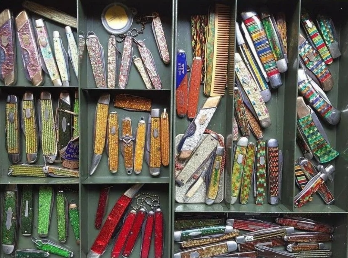 Zbierka farebných vreckových nožíkov so vzorovanými rukoväťami uložených v zásuvke.