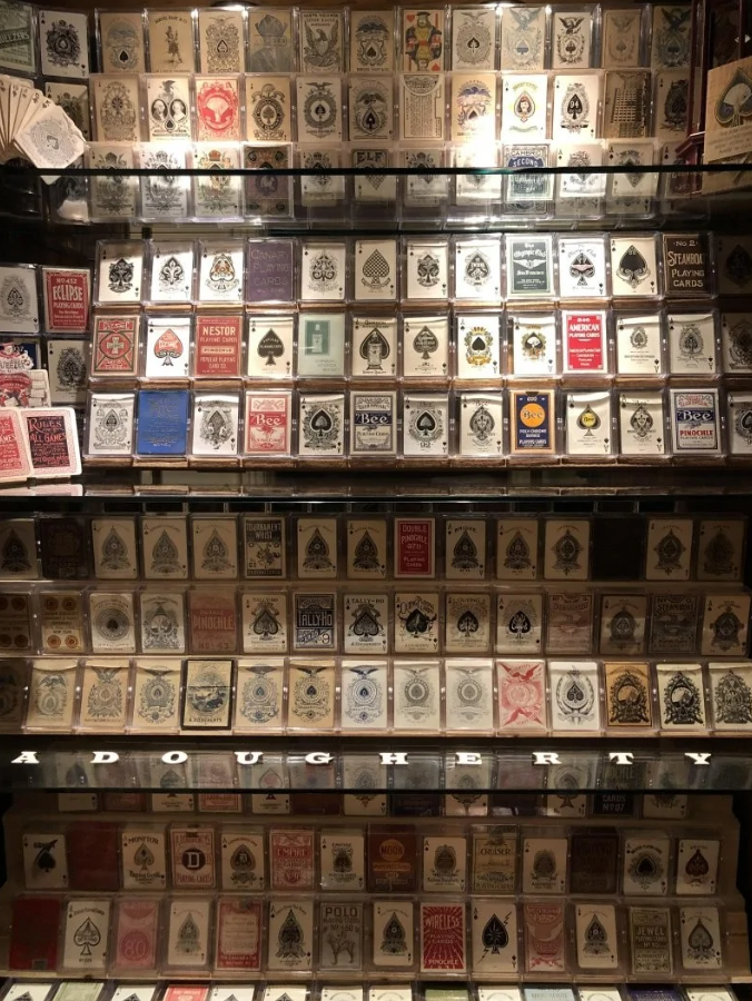 Zbierka historických balíčkov hracích kariet vystavených v osvetlenej vitríne.