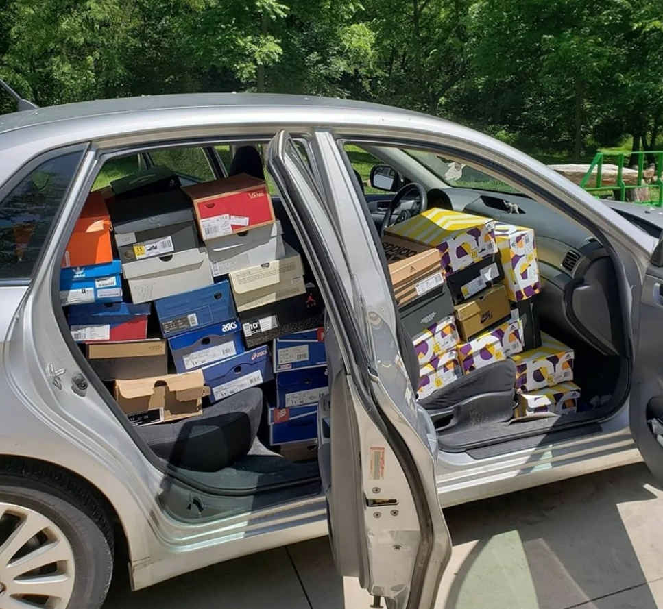 Auto naplnené krabicami od topánok zaparkované vonku na slnku, pohľad cez otvorené dvere.