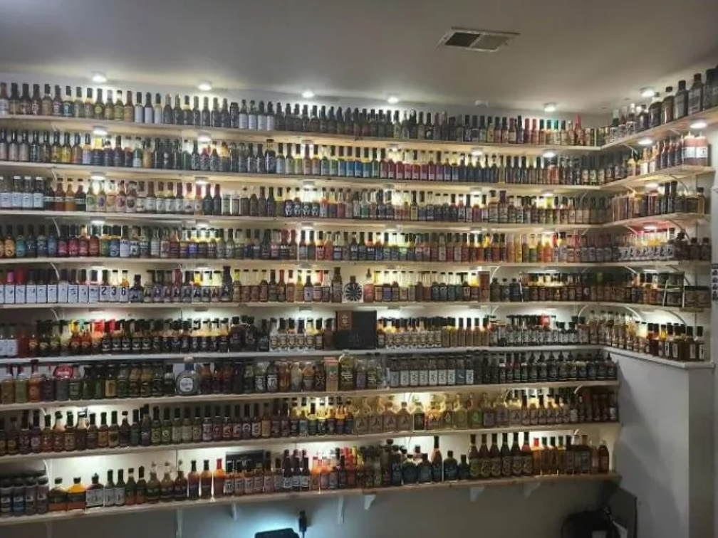 Regál plný pálivých omáčok rôznych značiek a chutí osvetlený LED svetlami v interiéri.