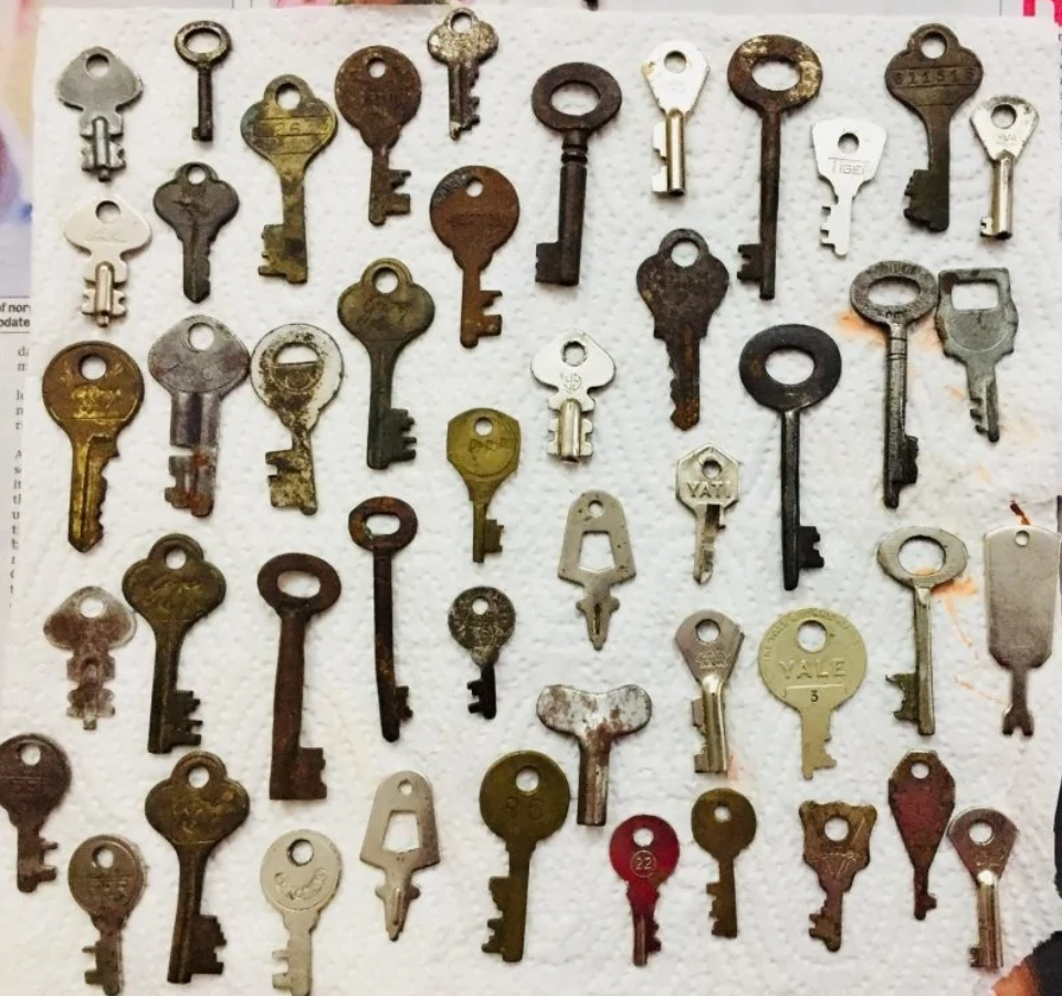 Stará kolekcia rôznorodých kľúčov na bielom pozadí. Rôzne tvary a veľkosti.
