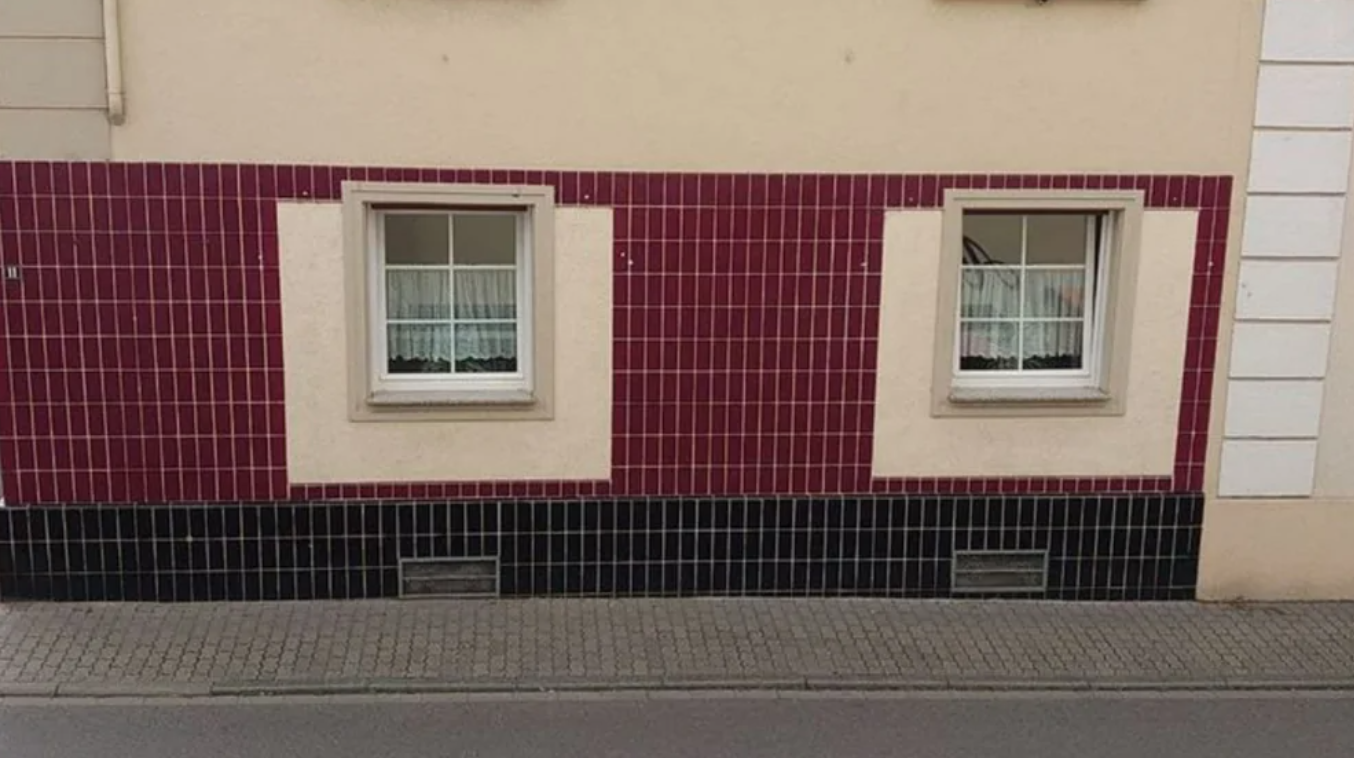 Dvojité okno na dome s bordovou kachličkovou stenou nad chodníkom.