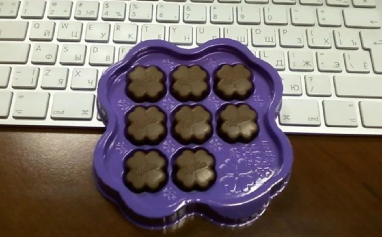 Fialový obal s čokoládovými kvetmi pred klávesnicou na drevenom stole.