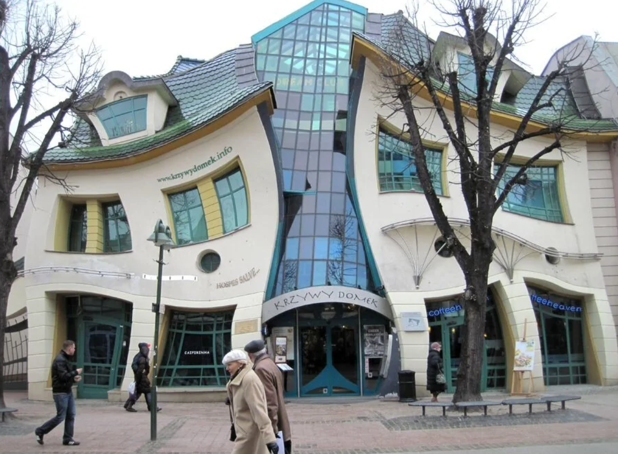 Zakrútená budova v Sopotach, Polsko, známa ako Krivý domček, s unikátnou architektúrou a vlnitým dizajnom.