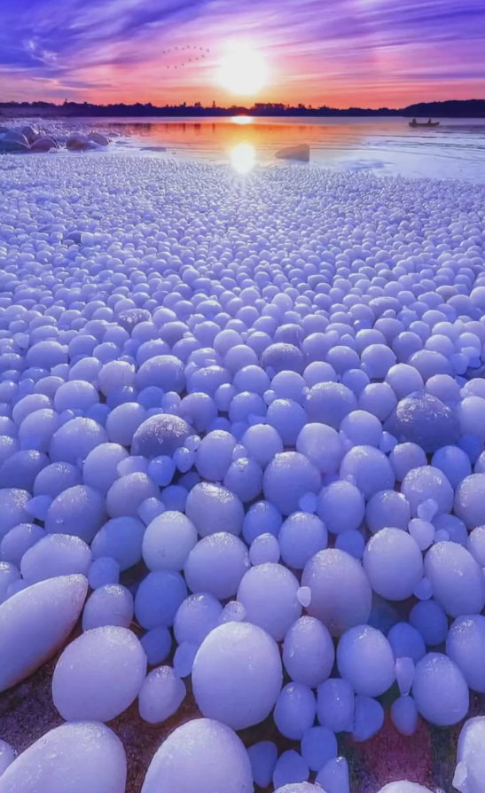 Jazero s guľovitým ľadom pri západe slnka, fialová obloha a pokojná voda.