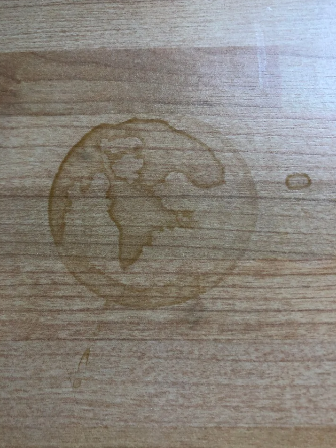 Kruhová stopa po pohári na drevenom stole pripomínajúca kontinent na mape sveta.