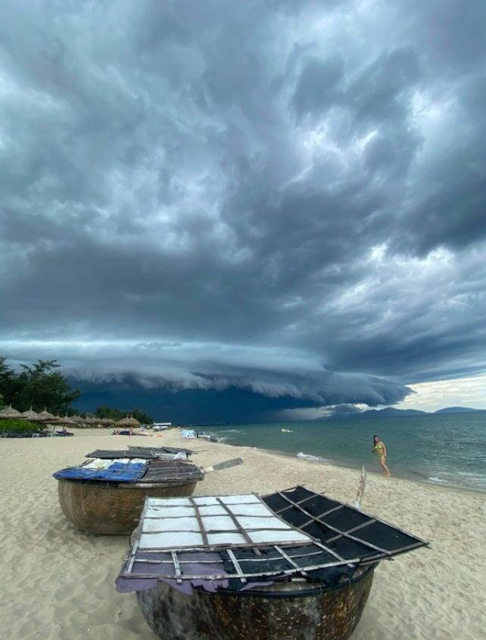 Búrka na pláži s oblakmi nad morom, loďky na piesku, dráma prírody sa blíži.