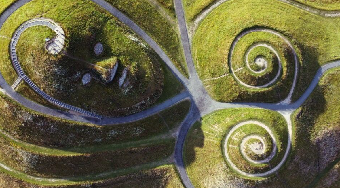 Letecký pohľad na kľukatú záhradnú krajinu s tvárou a špirálami vytvarovanou do zemného povrchu.