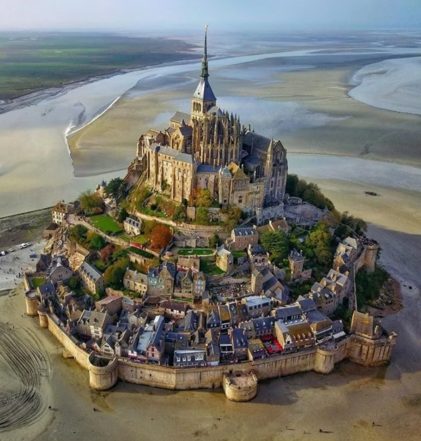 Historická pevnosť Mont Saint-Michel na skalnatom ostrove v Normandii, obklopená prílivovými vodami.