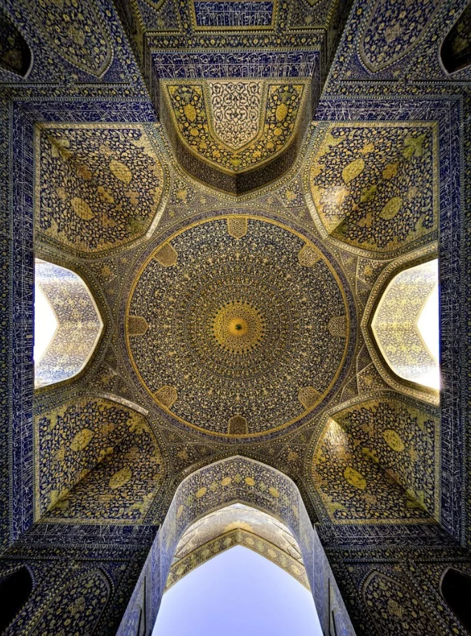 Bohatá ornamentálna výzdoba kupoly s modrou a zlatou mozaikou v islamskej architektúre.