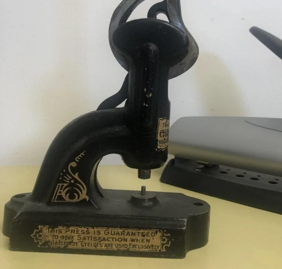 Starý lis na očká na stole vedľa moderného zariadenia, detailný pohľad.