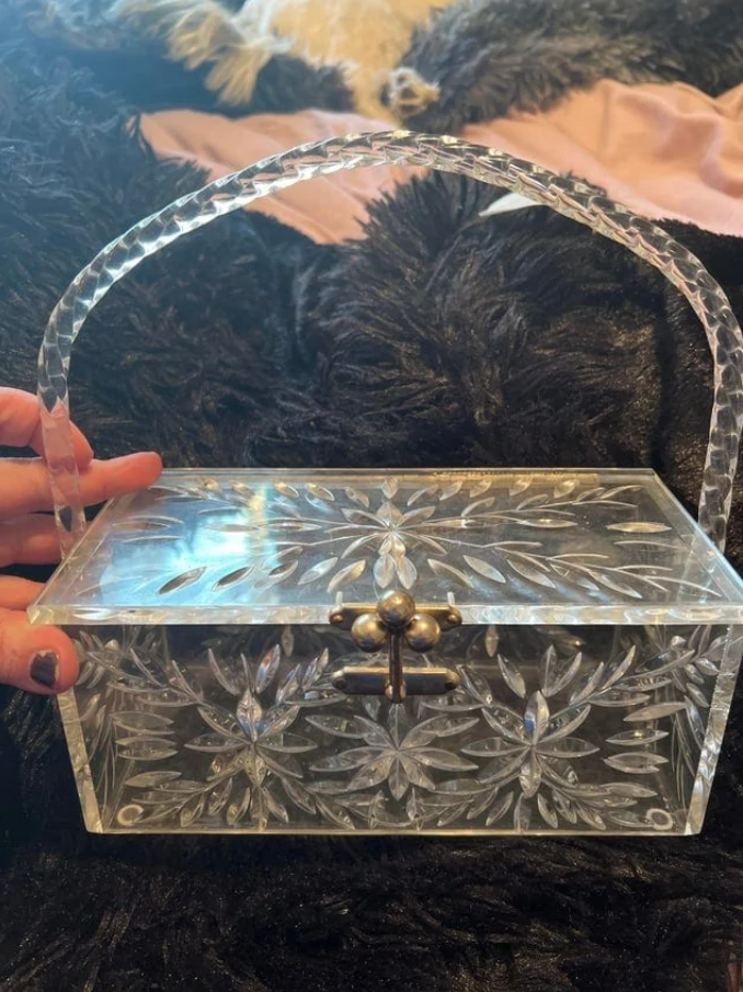 Priehľadná ozdobná plastová krabica s úchytom na čiernom pozadí, kvetinový vzor.