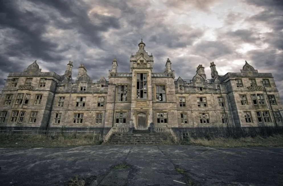 Opustená viktoriánska budova pod zamračenou oblohou, evokujúca tajomnú atmosféru.