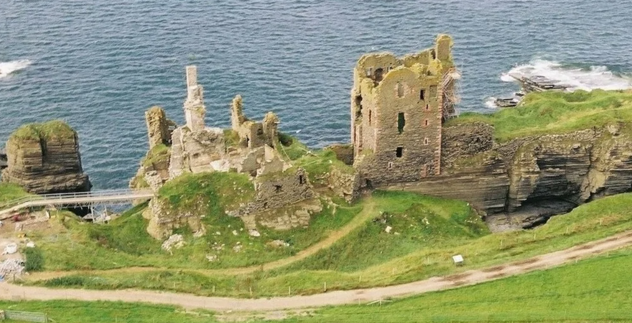 Starobylá zrúcanina hradu na útese s oceánom v pozadí. Malebný výhľad kombinujúci históriu a prírodu.