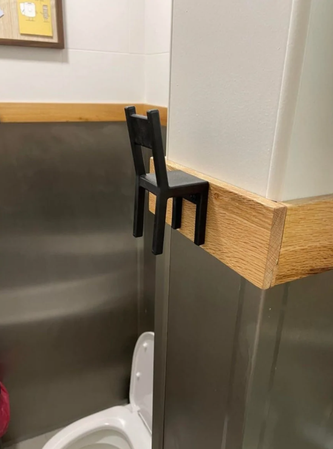 Miniatúrna stolička použitá ako držiak na kabelku vo verejnej toalete.