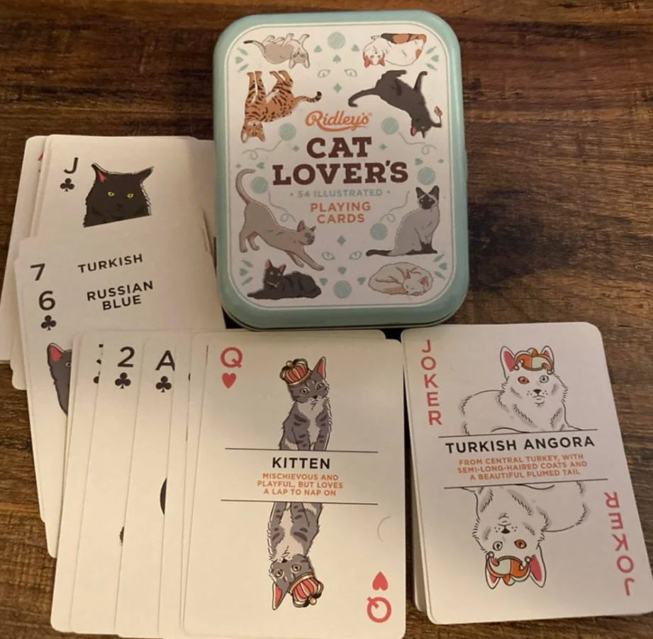 Kartová hra pre milovníkov mačiek s obrázkami rôznych plemien v kovovej krabičke na drevenom povrchu.