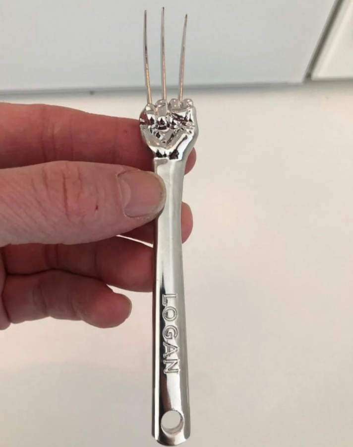 Vidlička v tvare pästi s vyrytým menom „LOGAN“, napodobňujúca ikonické pazúry komiksovej postavy.