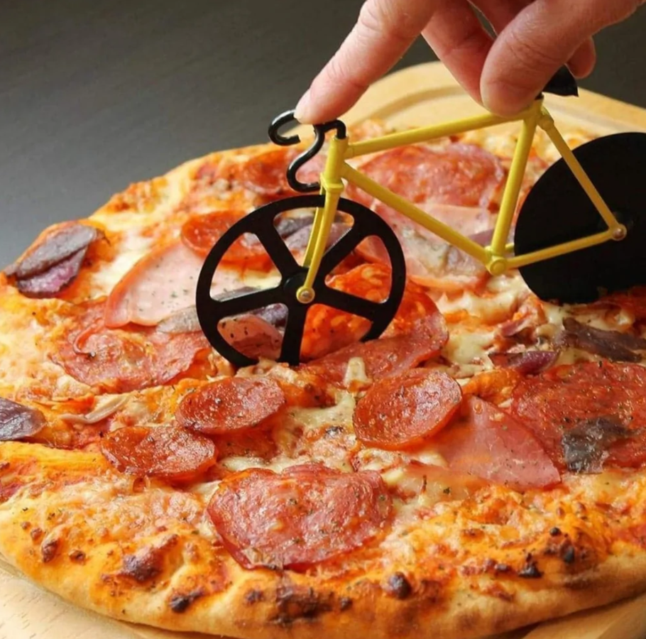 Rotačné koliesko na pizzu v tvare bicykla reže pepperoni pizzu, kreativný kuchynský doplnok.