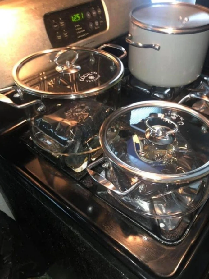 Tri hrnce na varnej doske: dva sklenené s pokrievkami a jeden veľký šedý hrniec vzadu.