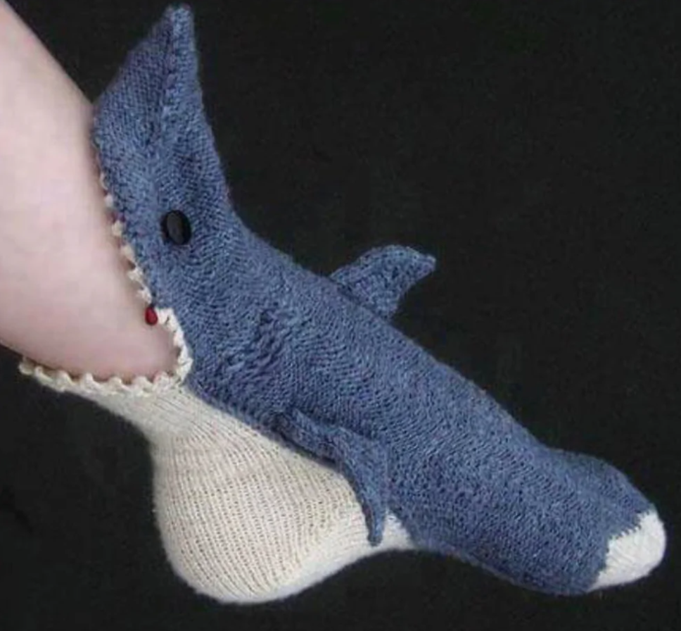 Pletená ponožka v tvare modrého žraloka na nohe, originálny a zábavný dizajn pre milovníkov morských motívov.